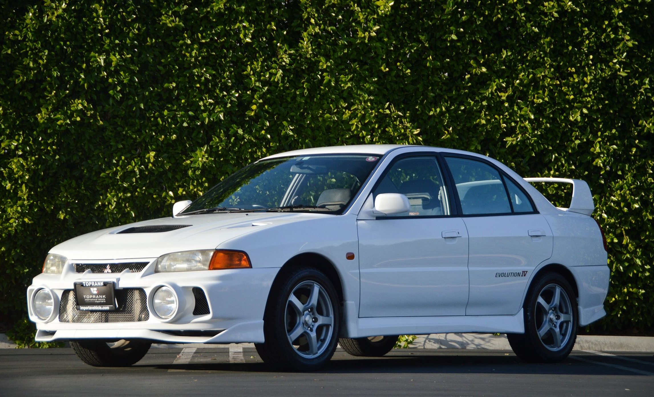 <p>The Mitsubishi Lancer Evolution IV, produced from 1996 to 1998, is a legendary rally-bred sedan renowned for its performance and handling. It features a turbocharged 2.0L inline-four engine paired with Mitsubishi's advanced all-wheel-drive system, delivering exceptional grip and agility on both tarmac and gravel surfaces. The Evolution IV marked a significant evolution in Mitsubishi's rally car lineage, incorporating advanced technologies and aerodynamic enhancements for improved performance. Its robust drivetrain and chassis make it a formidable contender on the rally stage and a favorite among performance enthusiasts. Additionally, the Evolution IV's turbocharged engine and AWD system offer ample potential for tuning, allowing owners to further enhance its already impressive performance capabilities. </p>:: Mitsubishi